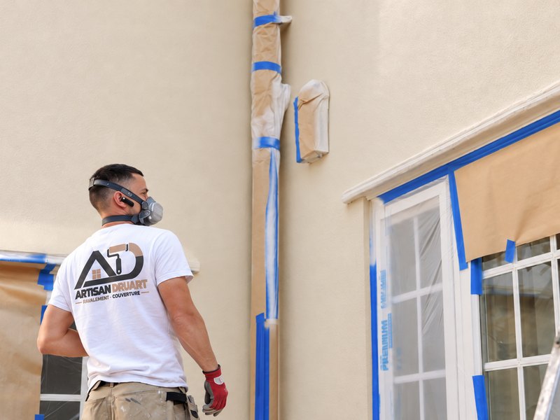 Artisan préparant une façade avant enduit : menuiseries et gouttière protégées